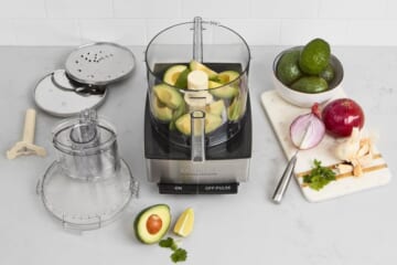 Cuisinart food processor next to accessories and avocados